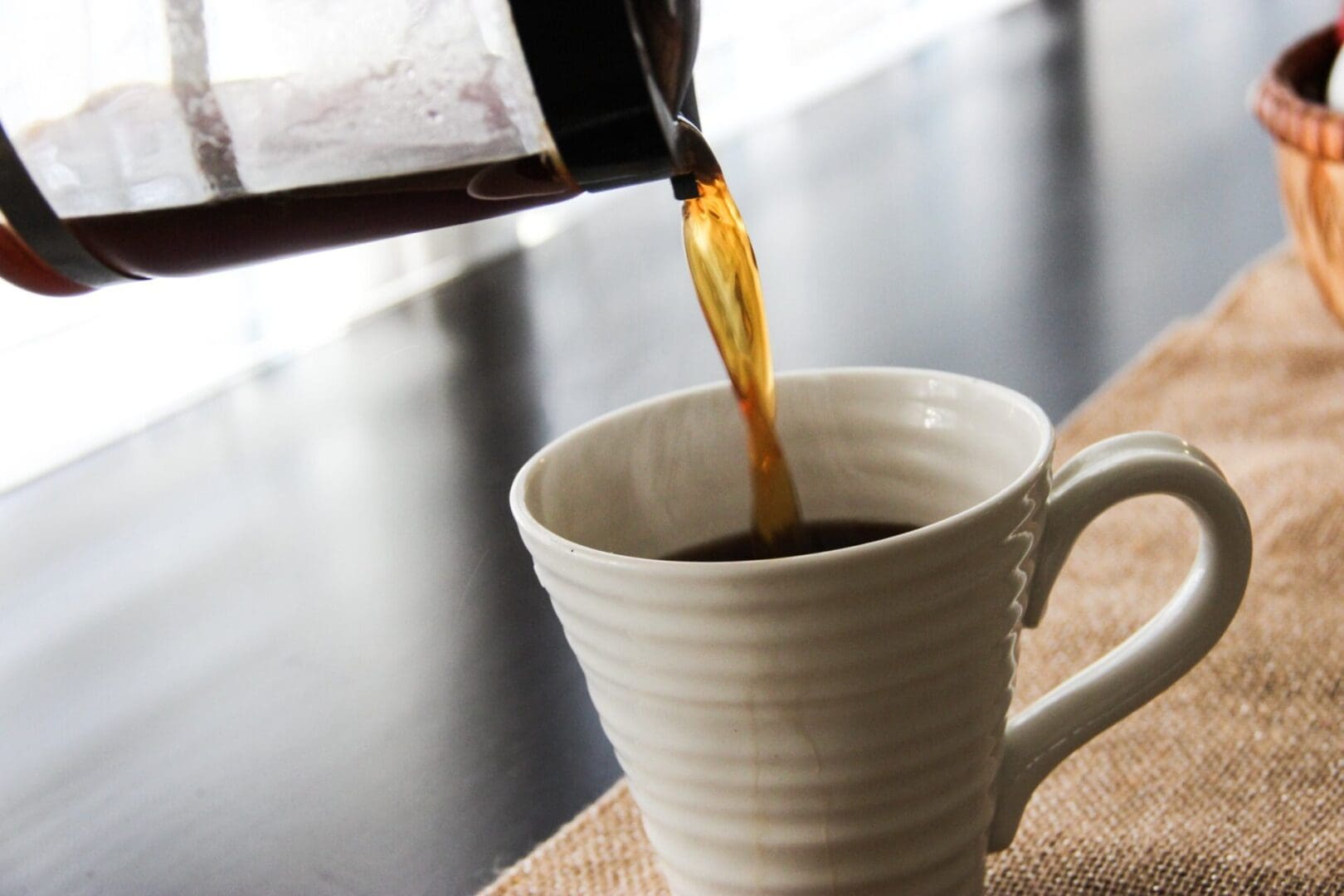 Pouring hot coffee into a white ceramic cup.