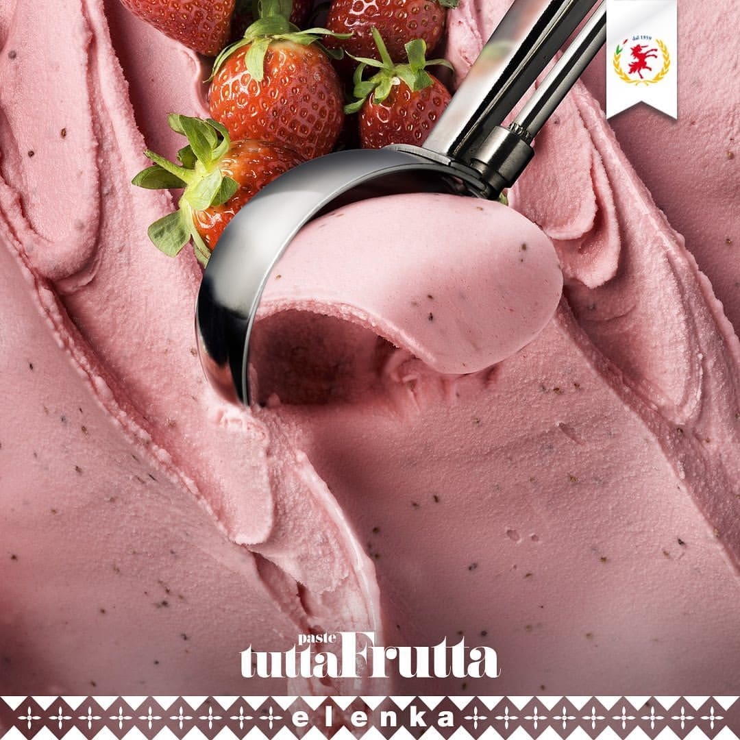 Close-up of a metal ice cream scoop holding Elenka Strawberry Fragola 100 ice cream, with strawberry pieces and swirls. Fresh strawberries garnish the scene. "Paste tuttaFrutta" and "elenka" are highlighted at the bottom.