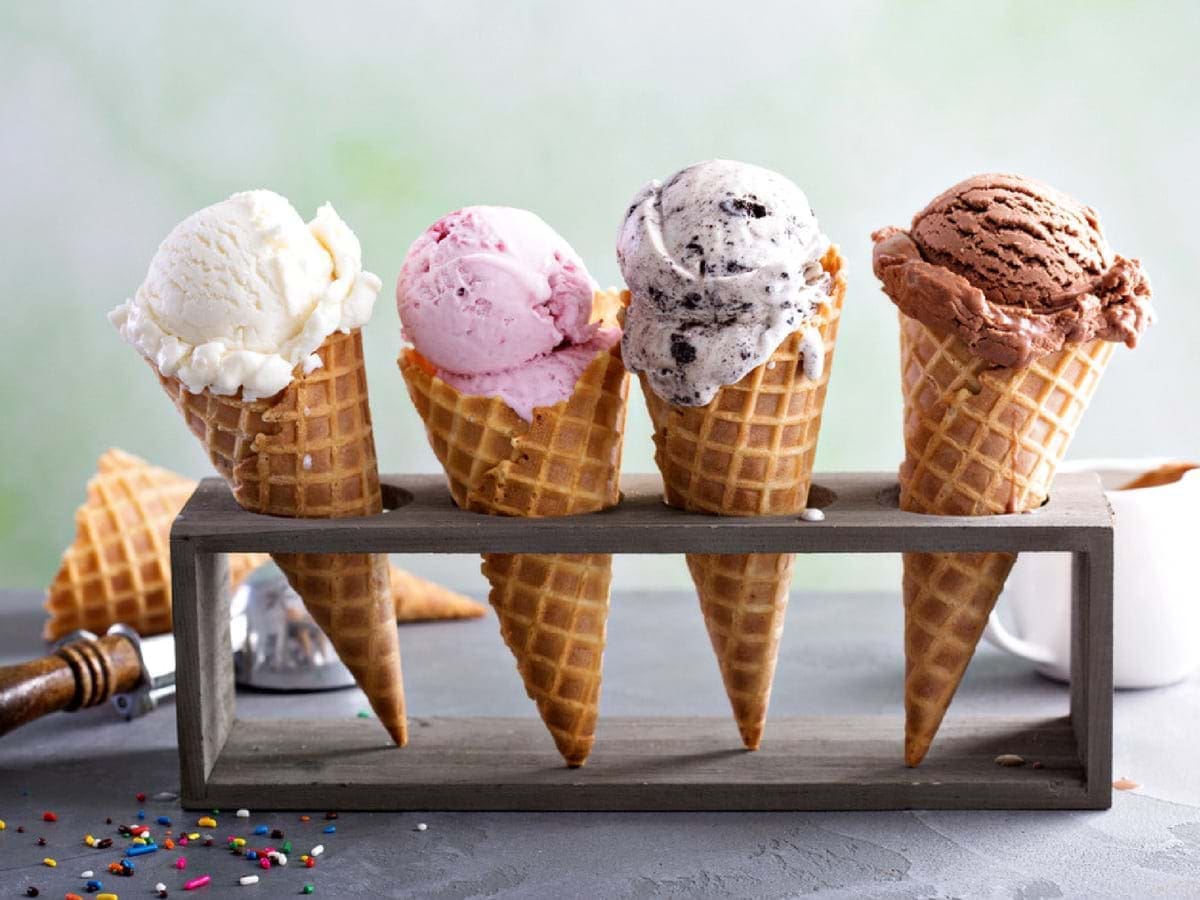 Four ice cream cones with different flavors in a metal holder.