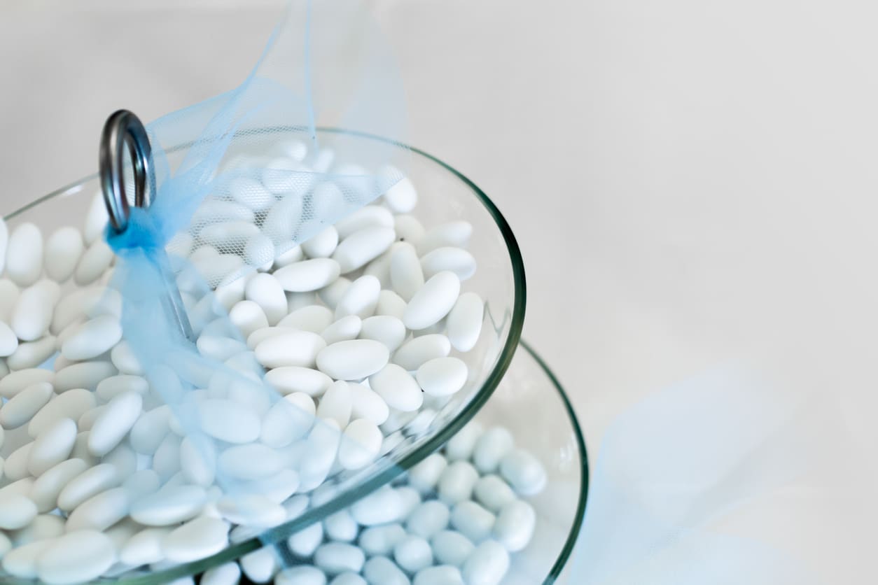 Close-up of white pills in glass bowls on a white surface.