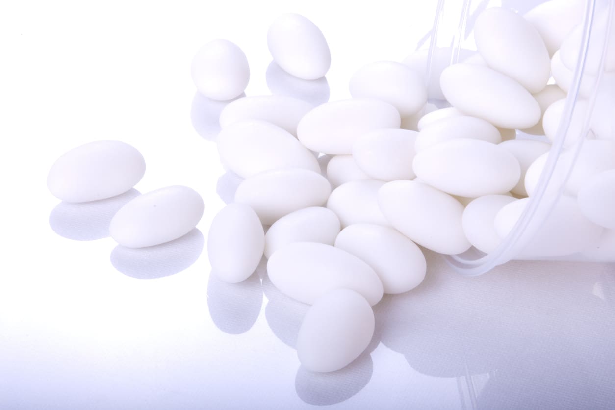 White oval pills scattered on a white surface.