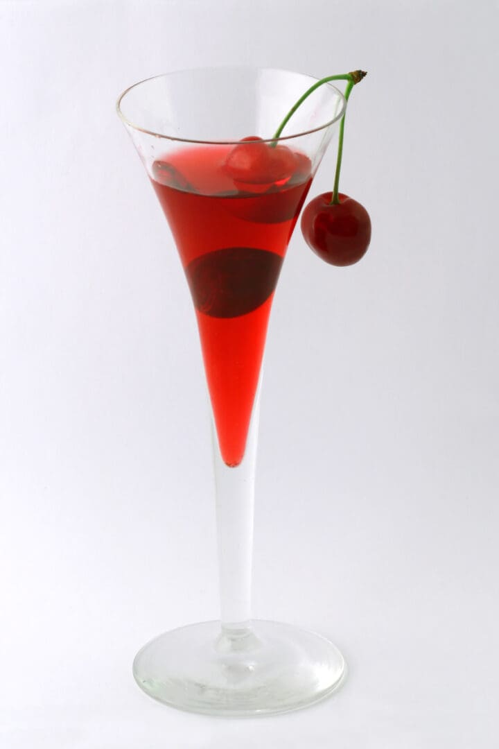 Elegant red cocktail with a cherry garnish in a tall glass.