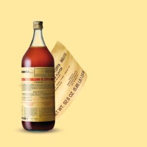 A large bottle of Elenka (303) Zuppa Inglese Extract, marked by its yellow label, is tilted against a light yellow background. Next to it, a curved floating instruction sheet offers more insights into this exquisite extract.