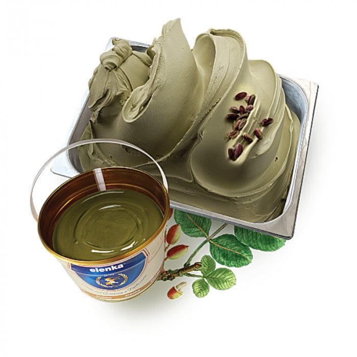 A tray of creamy pistachio gelato, garnished with whole pistachios, sits beside an open can of Elenka (775) Pistachio Pure Paste for Ice-Cream (4x2.5Kg per case), showcasing a colorful label brimming with images of leaves and nuts.