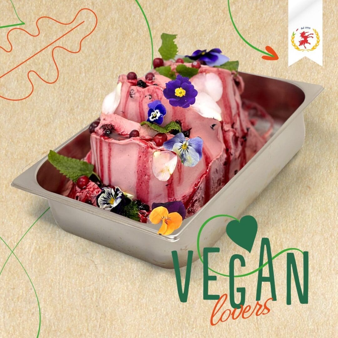 A metal tray of pink-veined vegan ice cream, featuring Luxardo Cherries, is adorned with edible flowers, mint leaves, and berries. "Vegan lovers" is elegantly penned in green and orange cursive on the lower right corner. A seal graces the upper right corner.