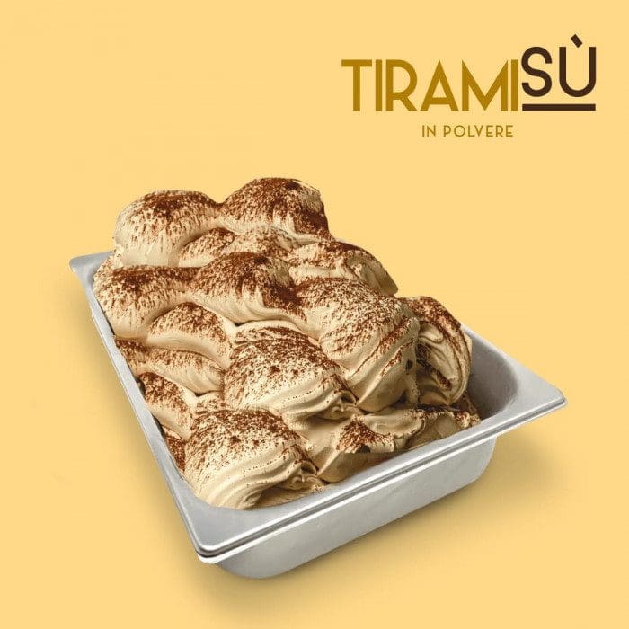 A metal tray filled with creamy tiramisu gelato, made using Elenka (443) Tiramisu Gelato Paste (2x6Kg case) and topped with cocoa powder, sits on a yellow background. "Tiramisù in polvere" appears in the top right corner.
