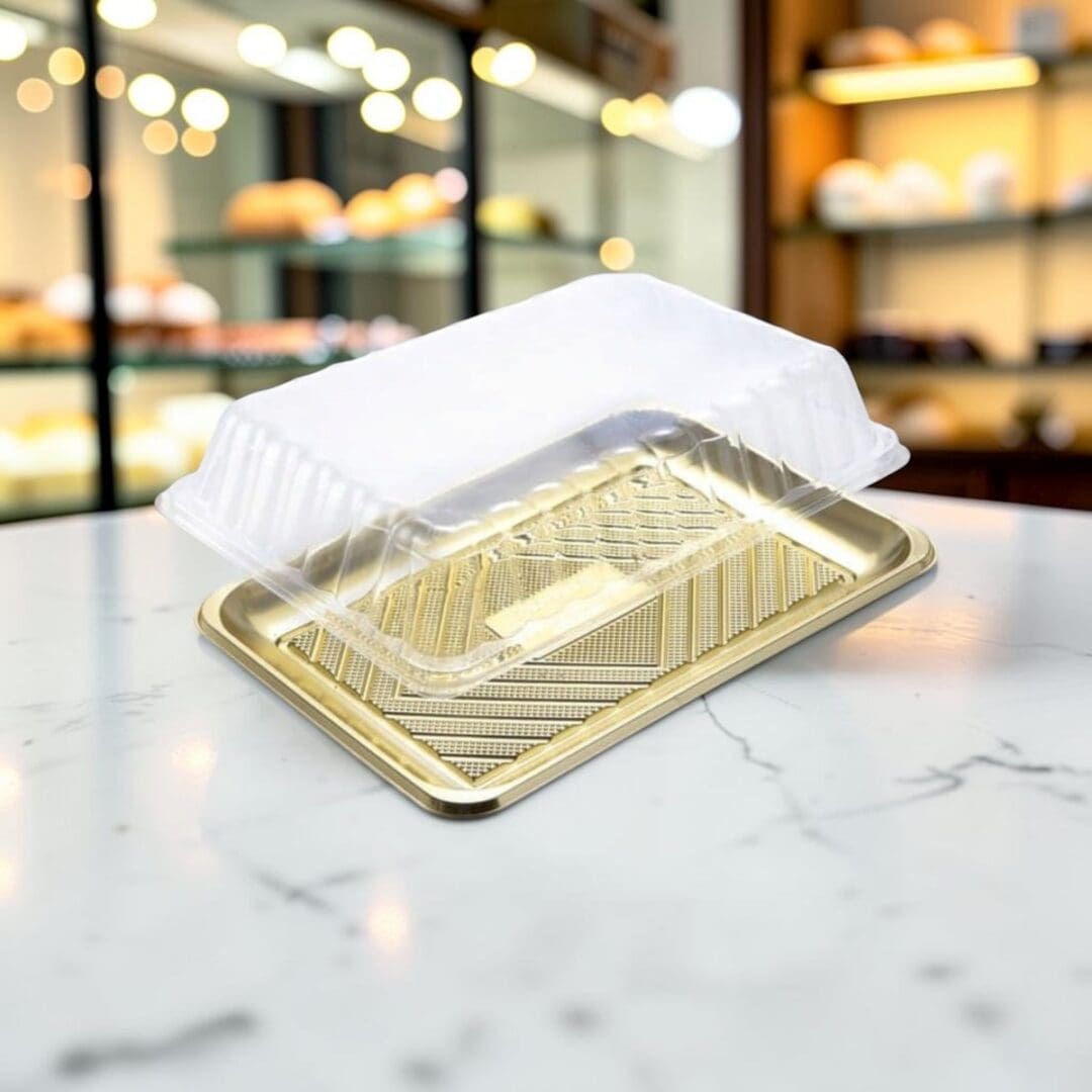 Alcas Kado gold pastry tray with clear lid on pastry shop counter