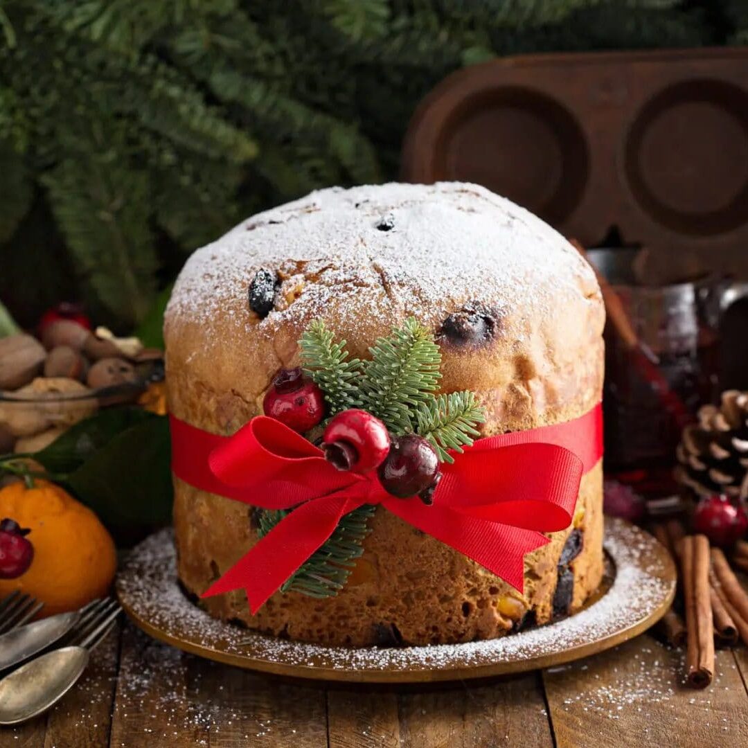 Festive panettone with red ribbon and Christmas decorations.