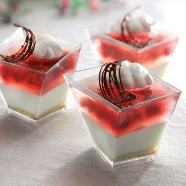 Layered dessert with creamy base, strawberry topping, and chocolate garnish in clear cups.